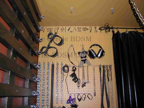 photo du haut du mur extrieur recouvert par le panneau trou, cot gauche et avec les jouets BDSM accrochs dessus